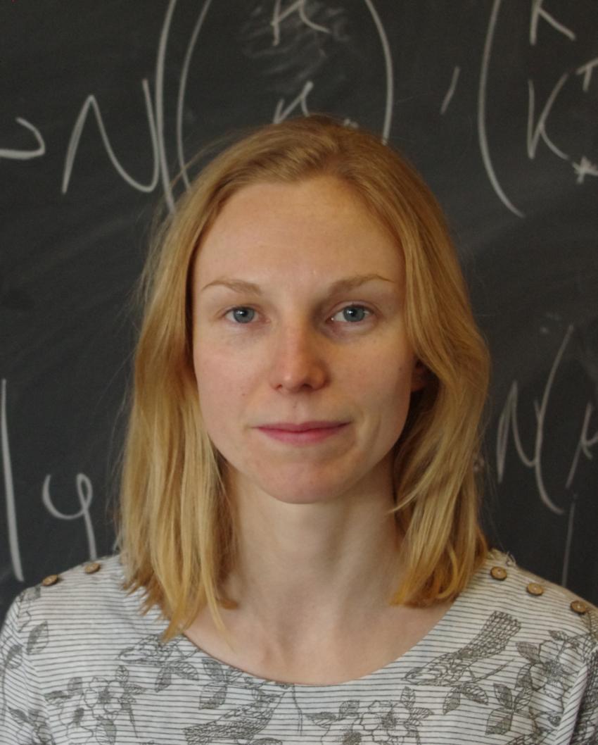 A photo of Rebecca in front of a blackboard