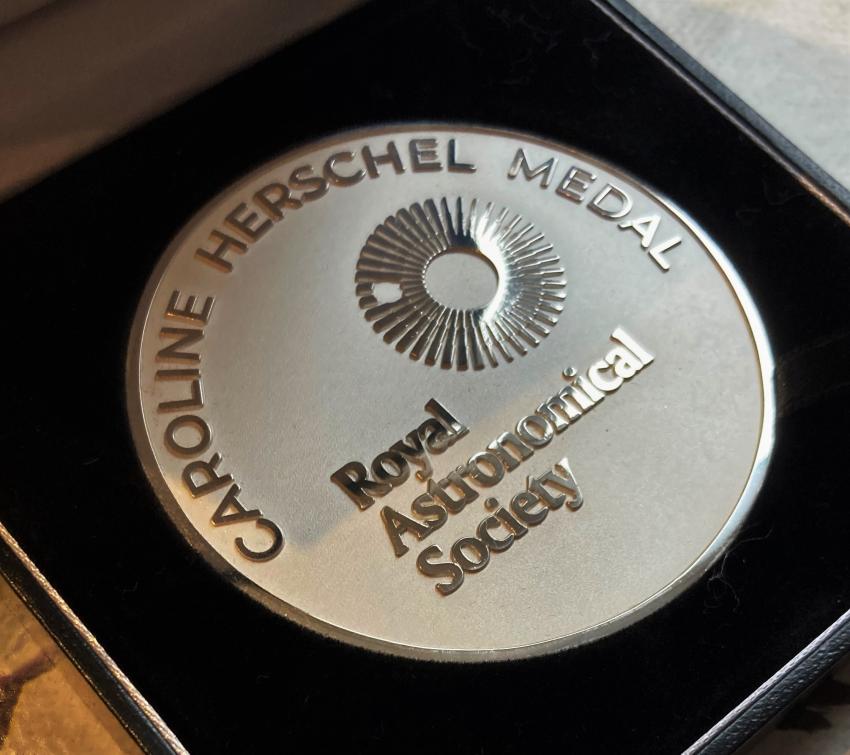 Image of the Caroline Herschel Medal. The medal is circular and appears to be silver, with the RAS logo engraved on the front. The words "Caroline Herschel Medal" are also engraved around the top edge of the medal.