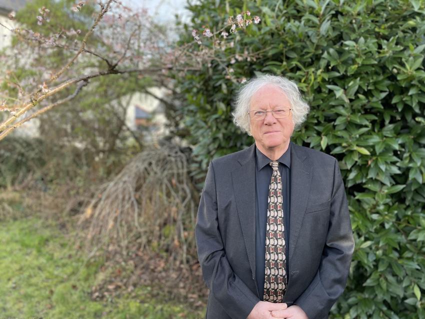 Image of Professor Mike Edmunds standing in front of trees and shrubs, smiling at the camera.