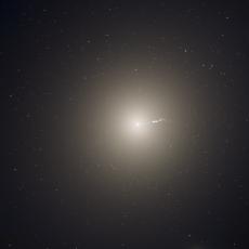 A bright white galaxy that is round in shape, glowing against the darkness of space.