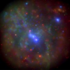 Multicoloured filaments in space surrounding a bright blue core, Sagittarius A*. The filaments appear to be red, and green, and look gaseous.